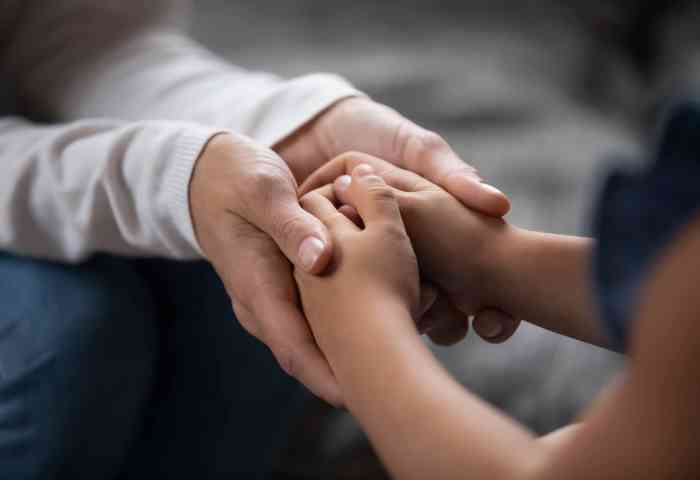 Adult holding a child's hands.