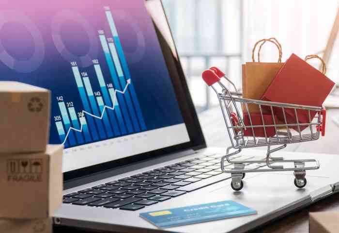 Laptop displays business growth graph with mini shopping cart on the keyboard