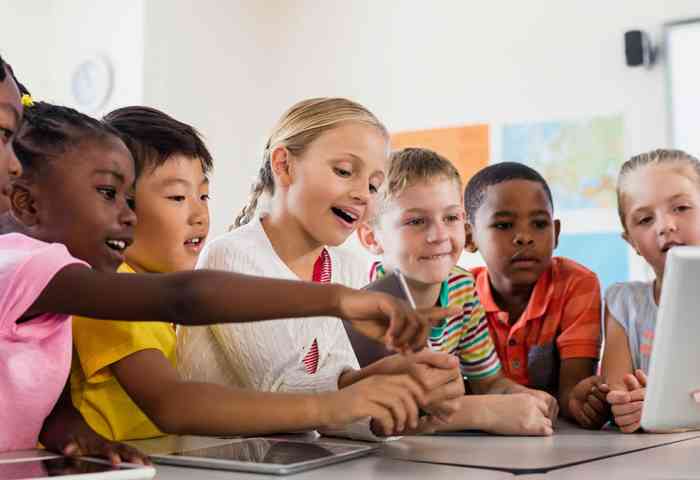 An elementary teacher showing material to a diverse group of elementary school students.