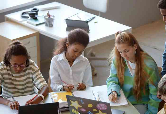 A teacher oversees a group of students working on a project.