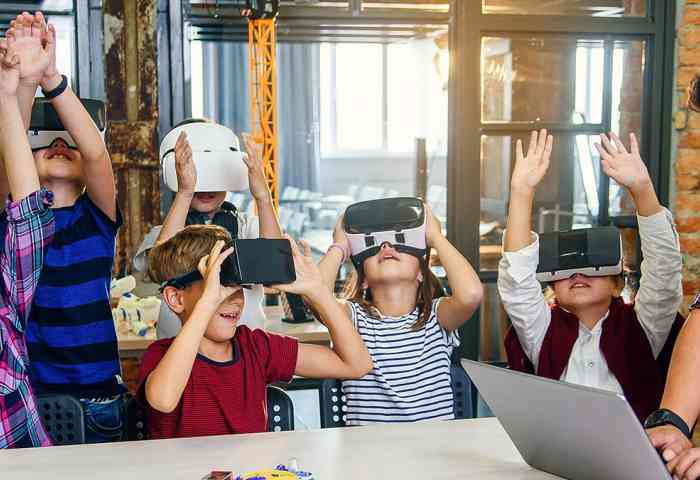 A teacher guides several young students through a VR experience.