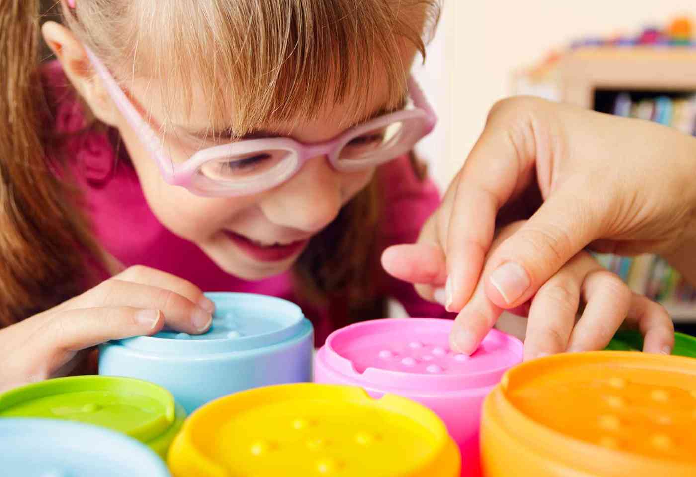 Hands of an occupational therapist helping a young child use some sensory toys.
