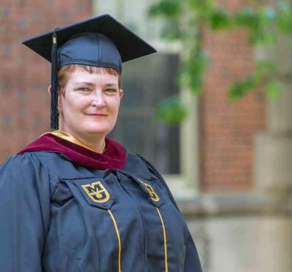 Penny Kittle, master's in youth development, wearing graduation cap and gown.