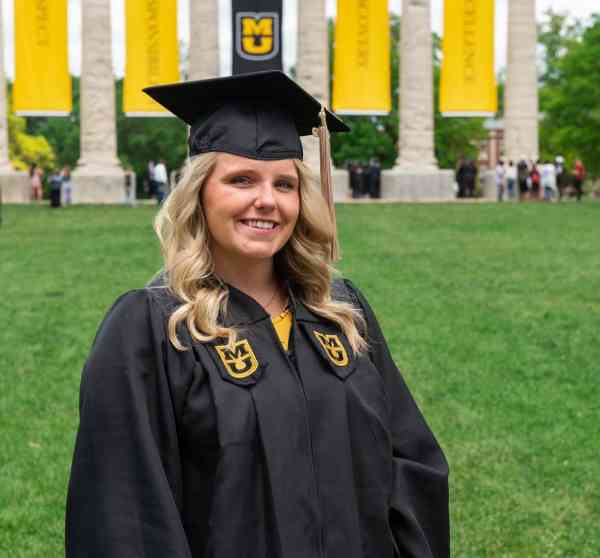 Sarah Swoboda, bachelor's in business administration ’19, wearing her graduation cap and gown, with the Mizzou columns behind her.