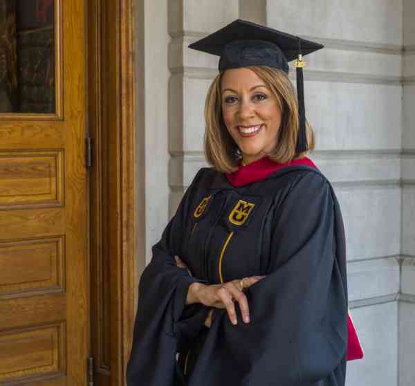 JoDee Kenney, MA in journalism, interactive media, wearing her graduation cap and gown.